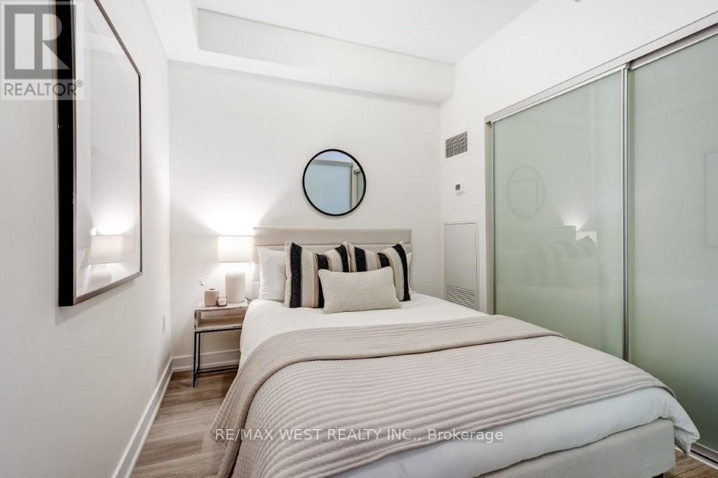A bedroom with a bed, nightstand, and a mirror on the wall.