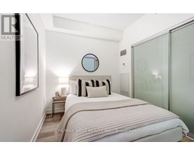 A bedroom with a bed, nightstand, and a mirror on the wall.