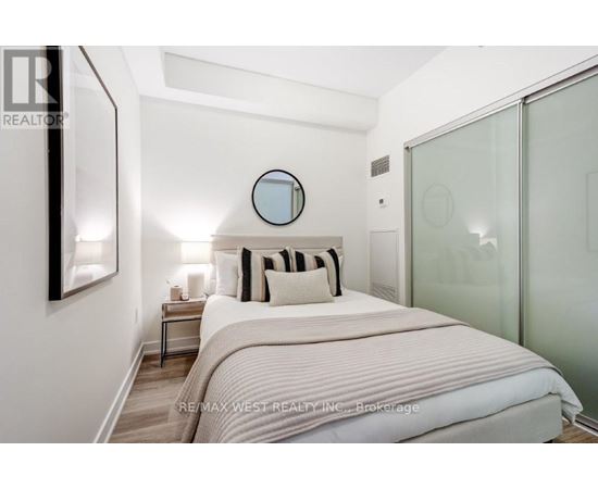 A bedroom with a bed, nightstand, and a mirror on the wall.