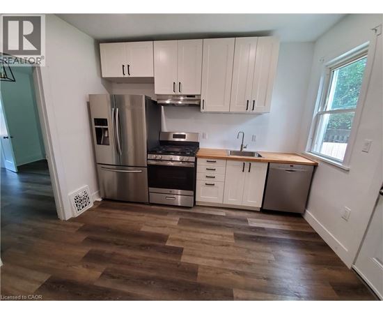 A kitchen with white cabinets and a wooden floor.