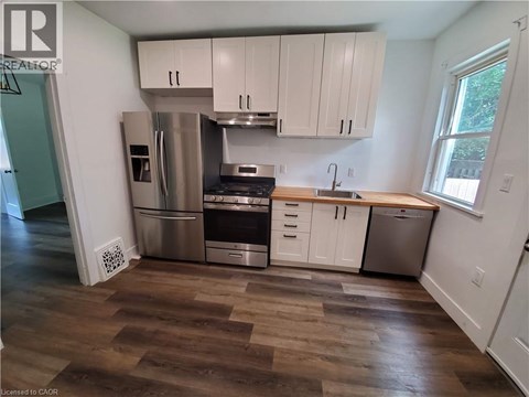 A kitchen with white cabinets and a wooden floor.