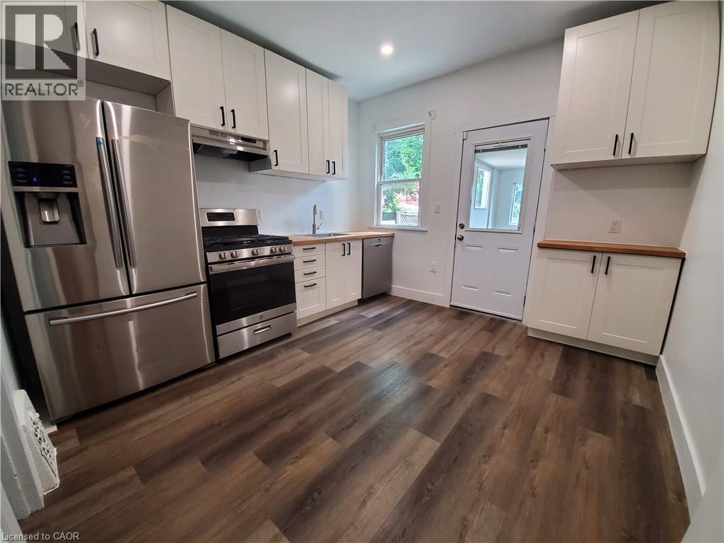 A kitchen with white cabinets and a wooden floor.