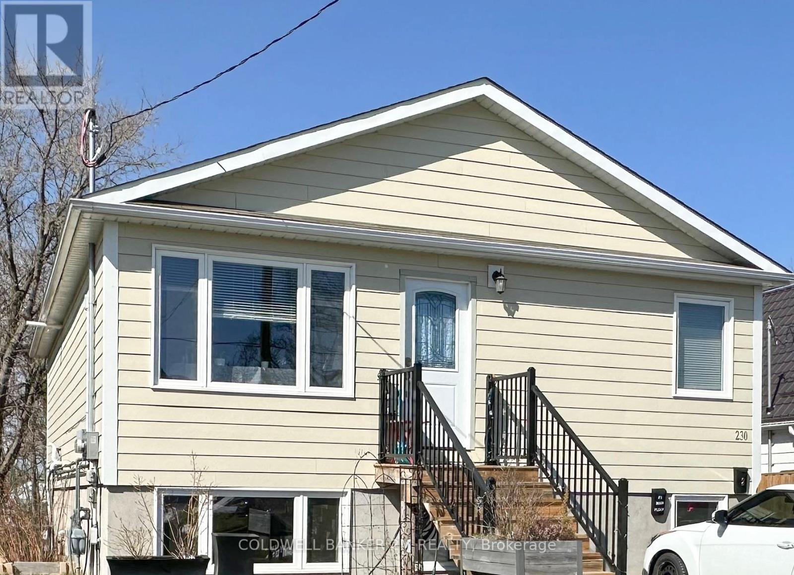 A house with a beige siding and a white car parked in front.