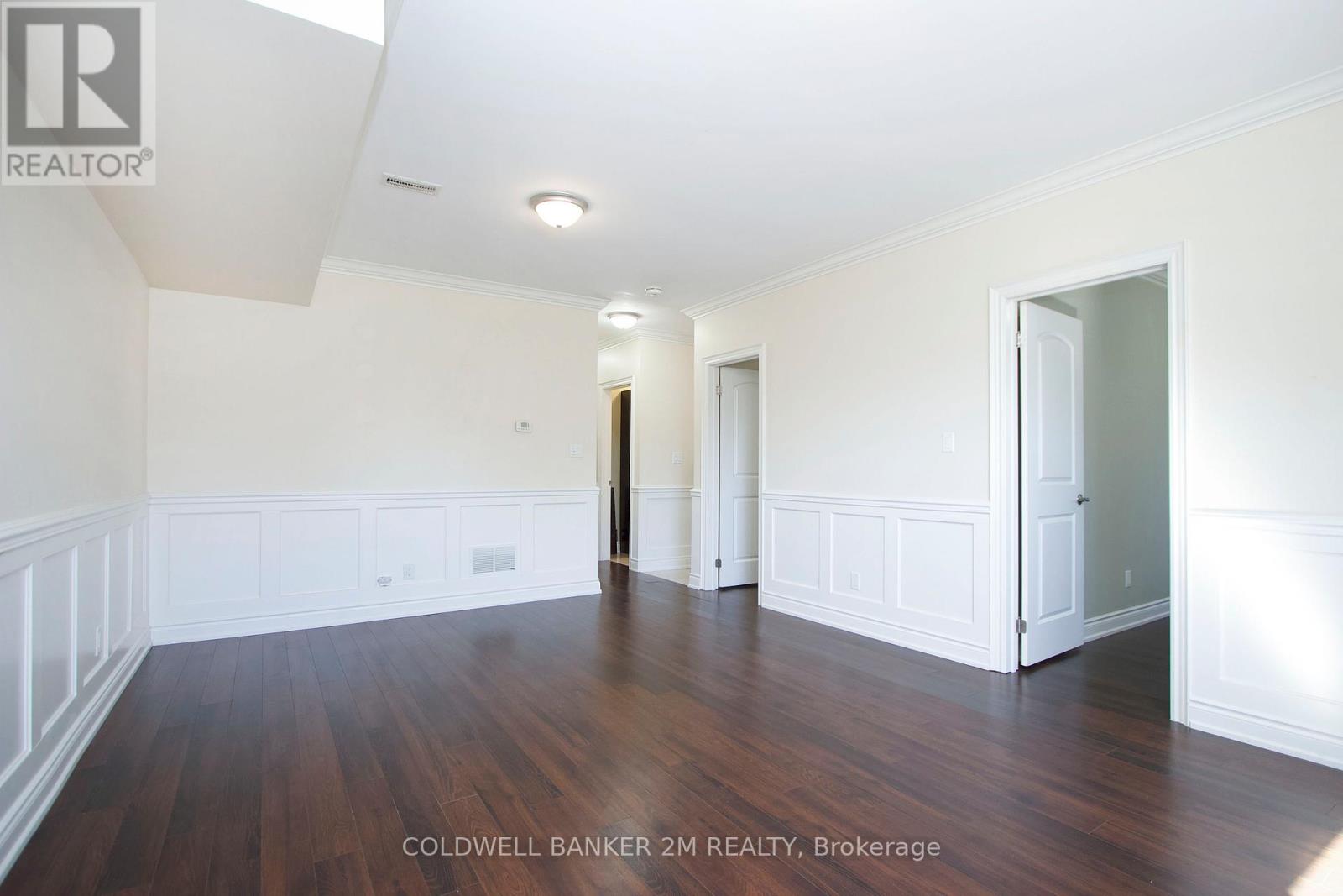 A spacious room with wooden floors and white walls.