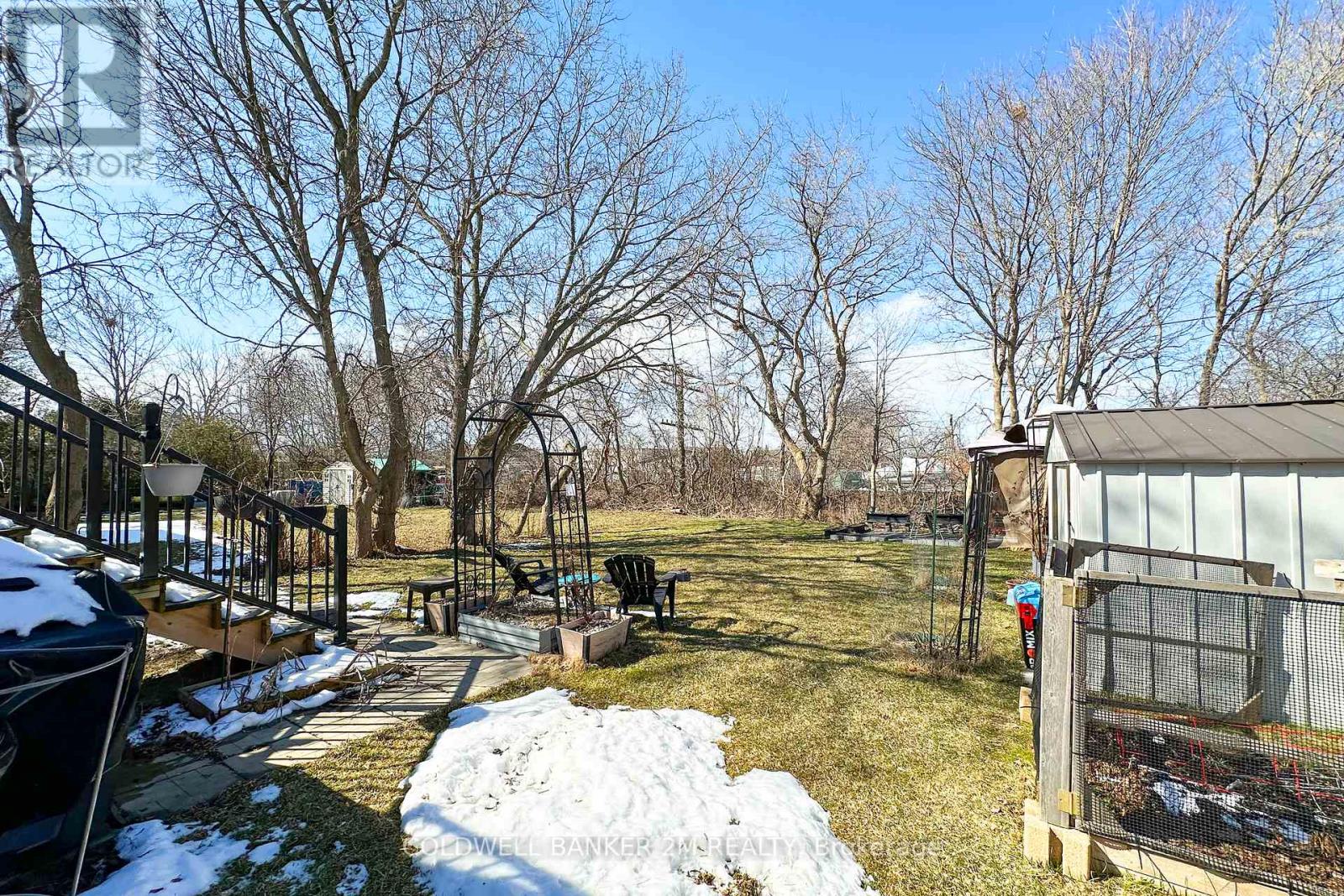 A backyard with a fence, a small pond, and a covered grill area.