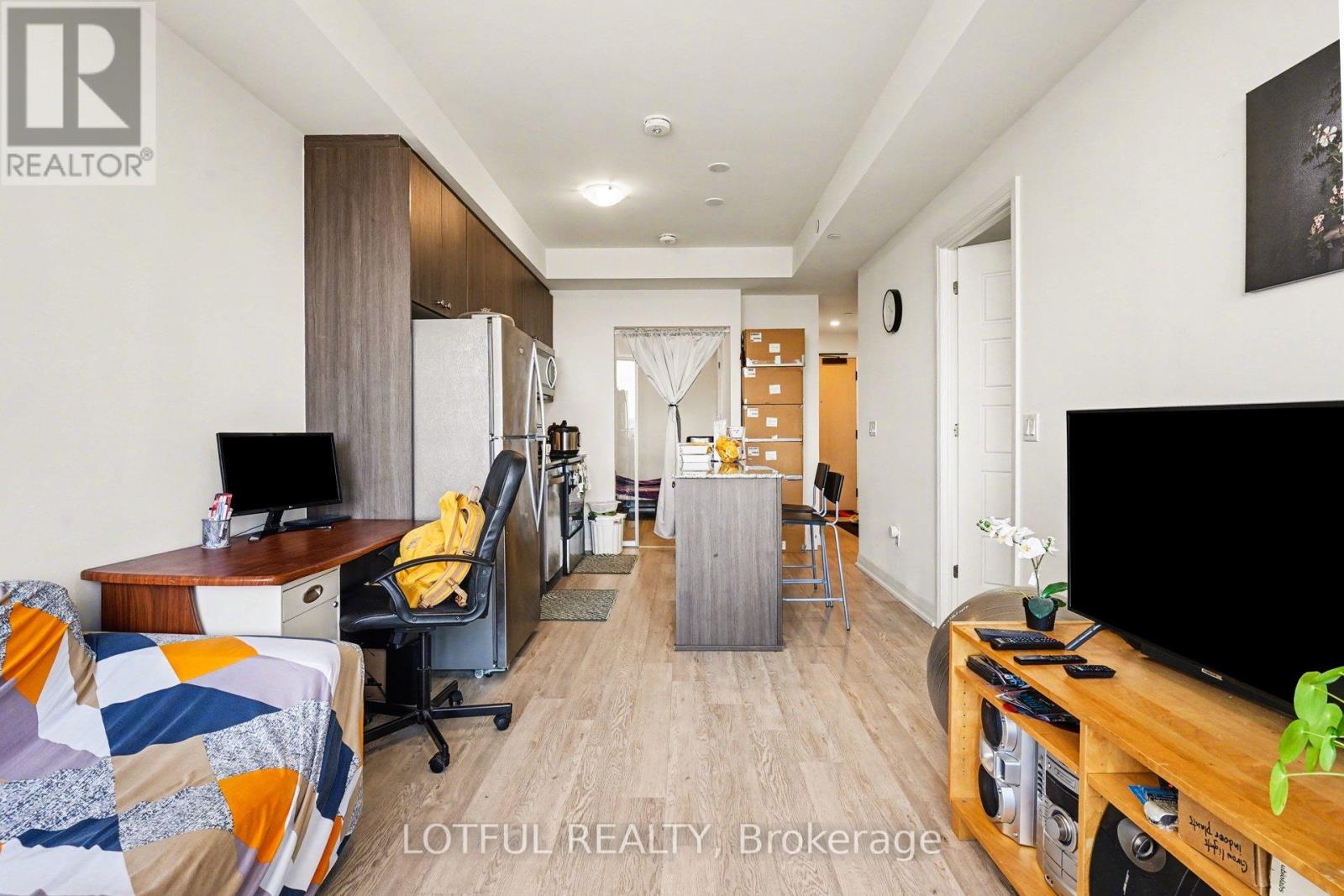 A living room with a couch, a chair, a desk, and a television.