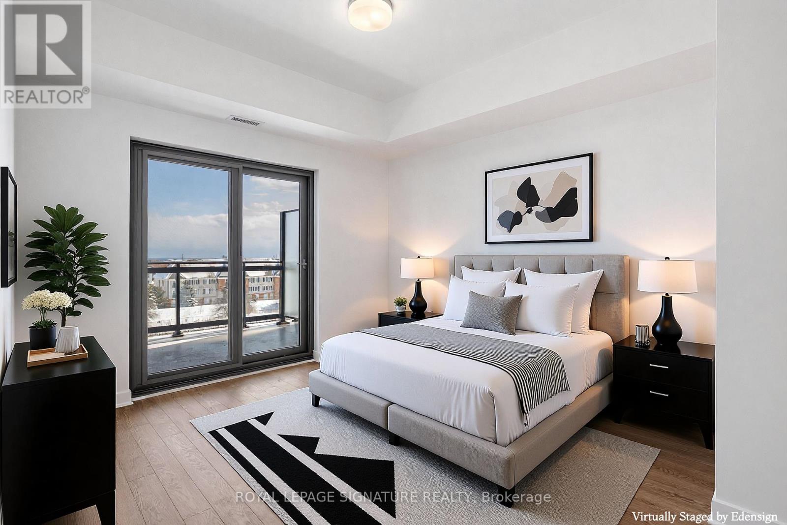 A bedroom with a large bed, a plant, and a view of the city through the window.