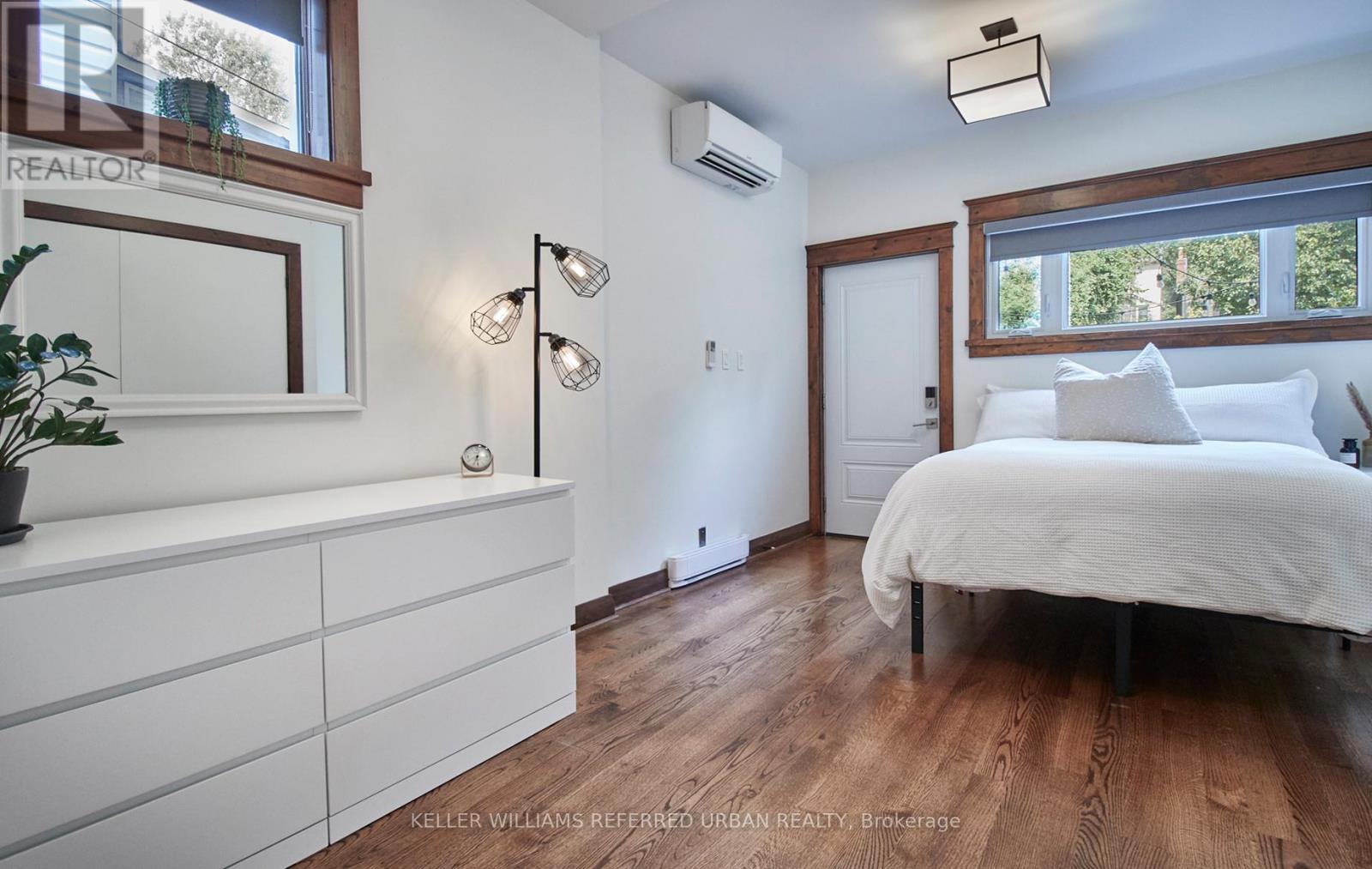 A bedroom with a white bed and wooden floors.