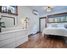 A bedroom with a white bed and wooden floors.