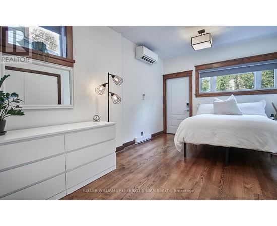 A bedroom with a white bed and wooden floors.