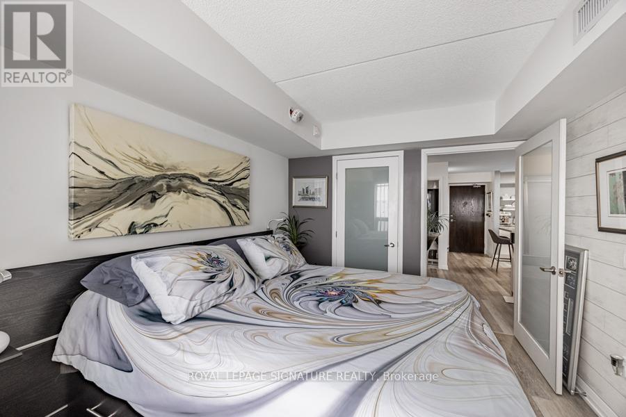 A bedroom with a large bed and a painting on the wall.