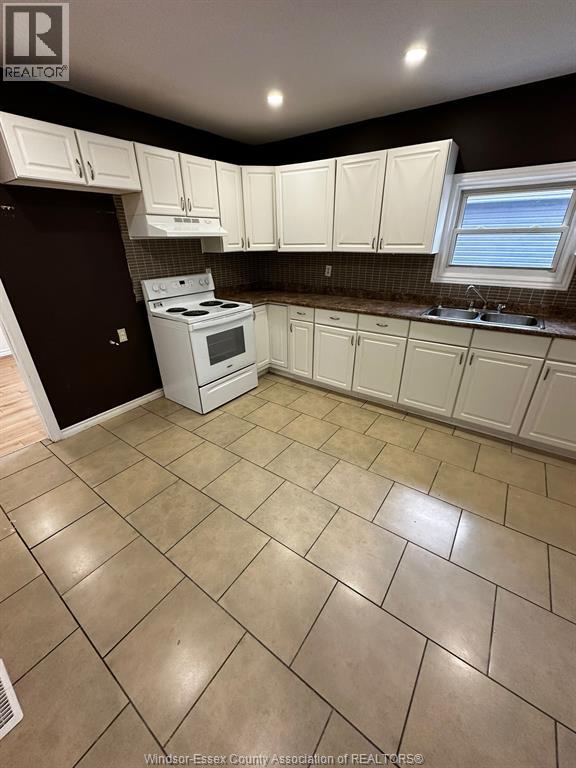 A kitchen with white cabinets and a white stove top oven.