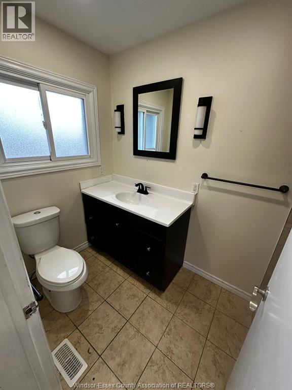 A bathroom with a toilet, sink, and mirror.