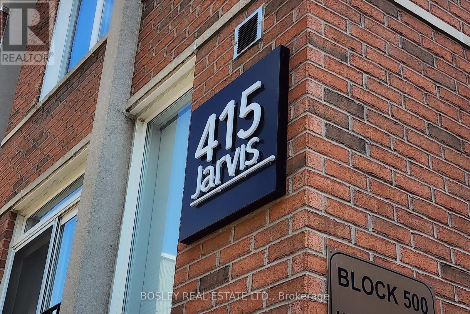 A sign for 415 Jarvis is displayed on a brick building.