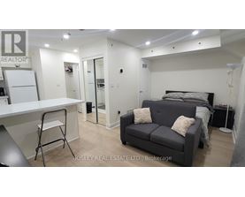 A real estate listing image of a bedroom with a bed, couch, and desk.