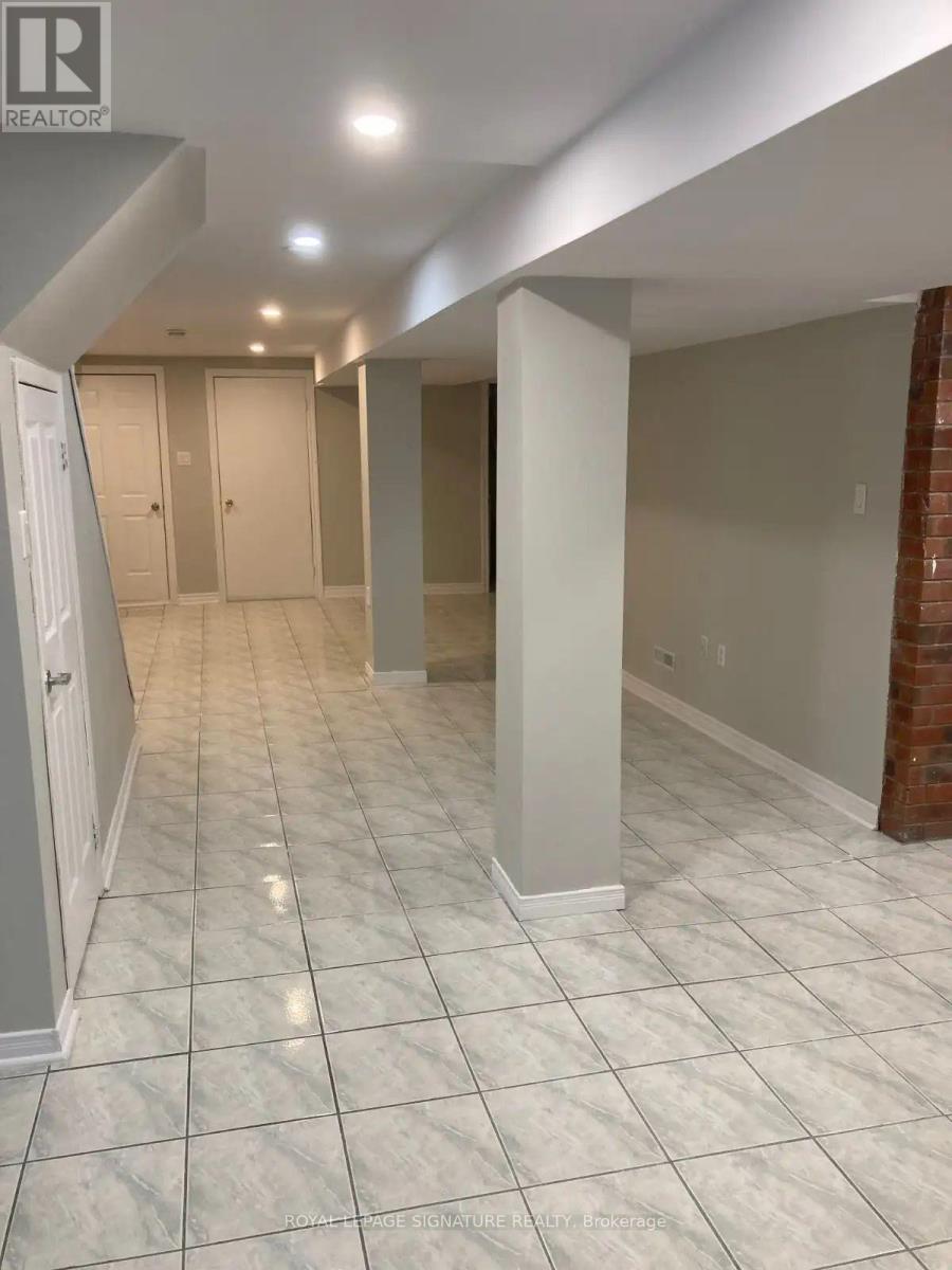 A spacious hallway with white tiled floors and a brick wall on the side.