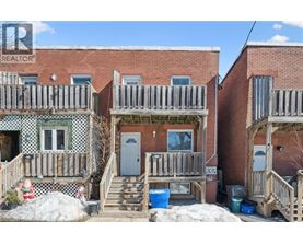A realtor photo of a brick house with a porch.