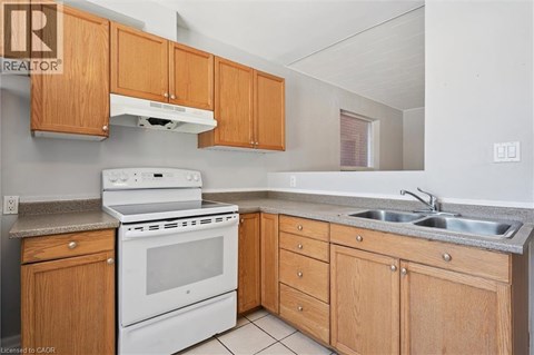A kitchen with wooden cabinets and a white stove top oven.