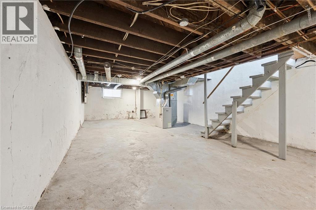 A spacious basement with a staircase and exposed pipes.