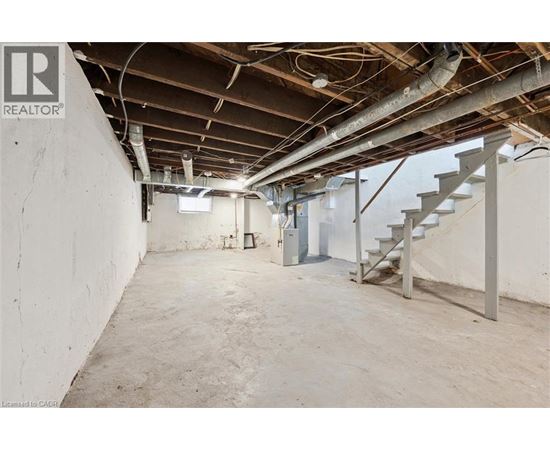 A spacious basement with a staircase and exposed pipes.