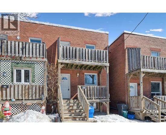 A red brick building with a balcony and a door.