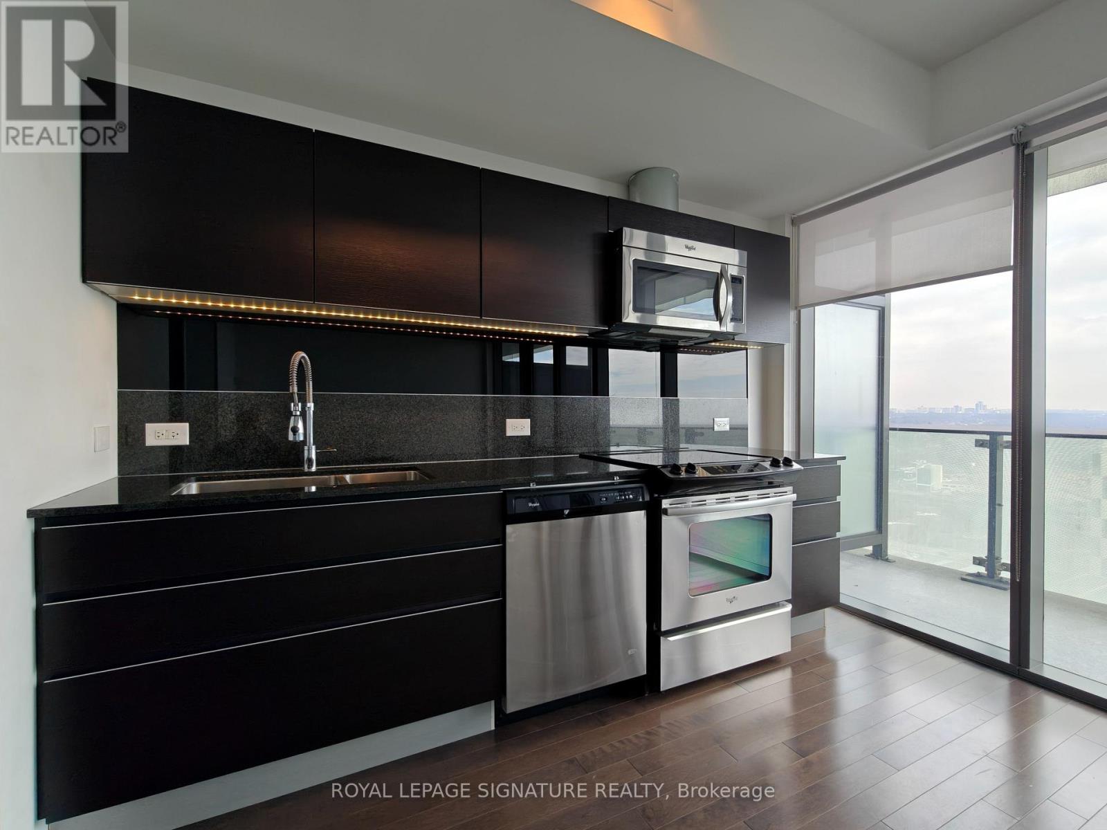 A modern kitchen with black cabinets and stainless steel appliances.