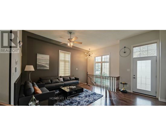 A living room with a black couch and a ceiling fan.