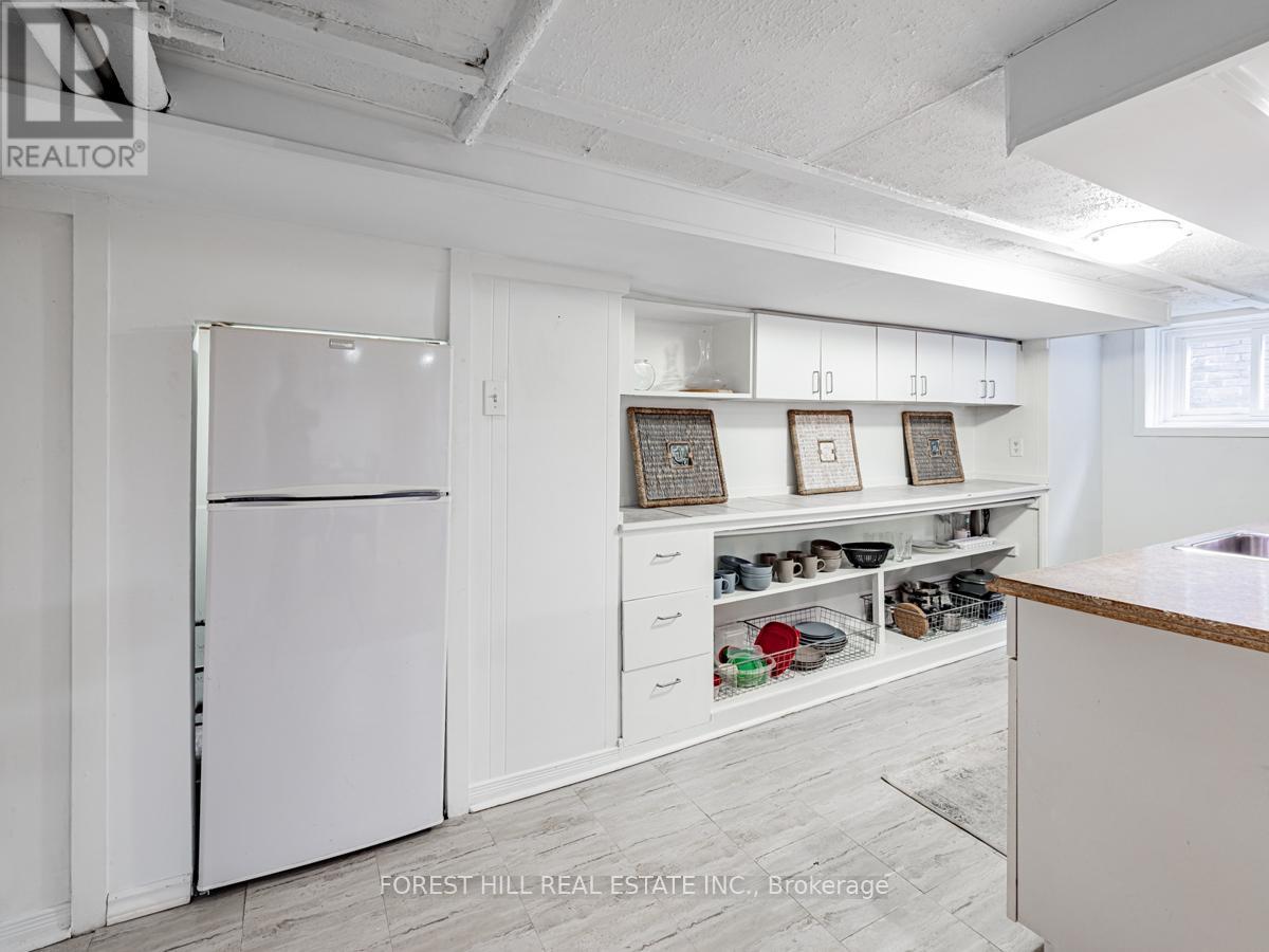 A white refrigerator is in a kitchen with white cabinets and drawers.