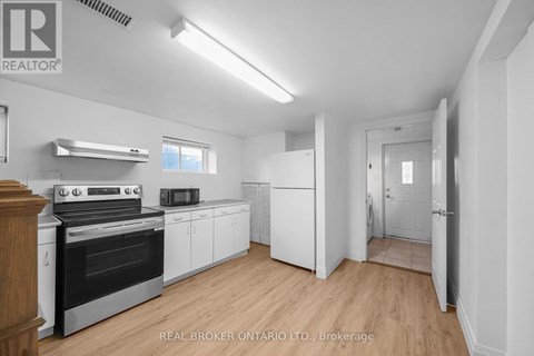 A white kitchen with wood floors and a stove top oven.