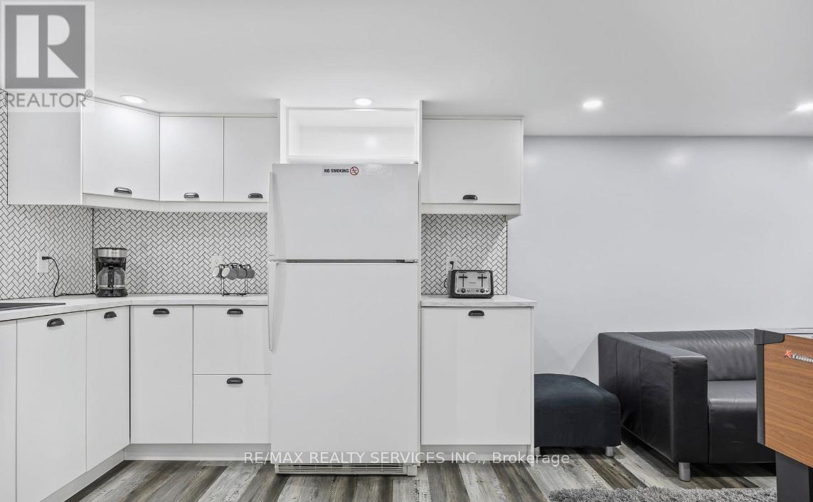 A white refrigerator is in the middle of a kitchen with a black and white checkered backsplash.