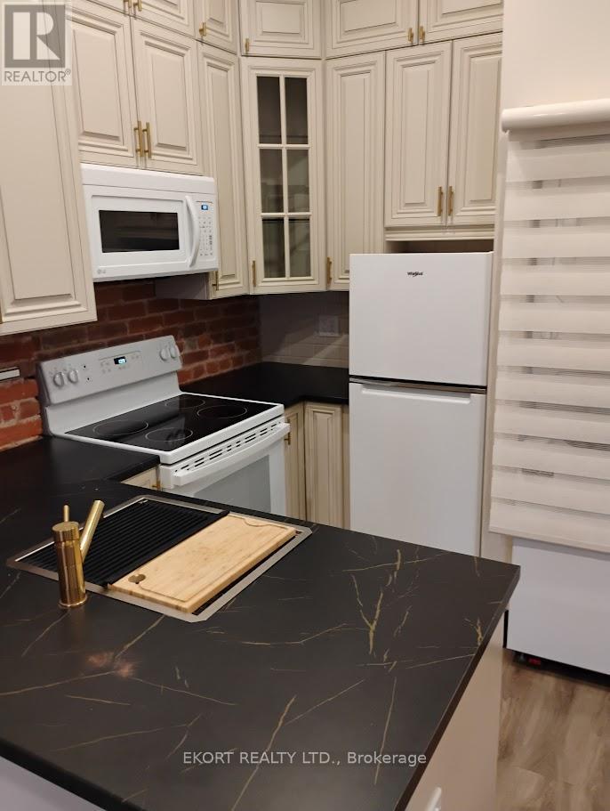 A kitchen with a black counter top and white appliances.