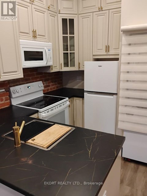 A kitchen with a black counter top and white appliances.