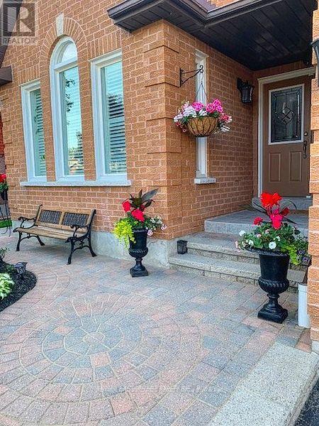 A brick house with a brown door and a flower pot on the steps.