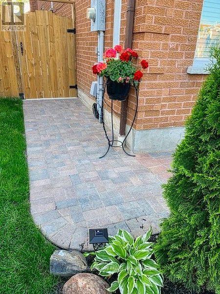 A brick wall with a planter on top and a wooden fence in the background.