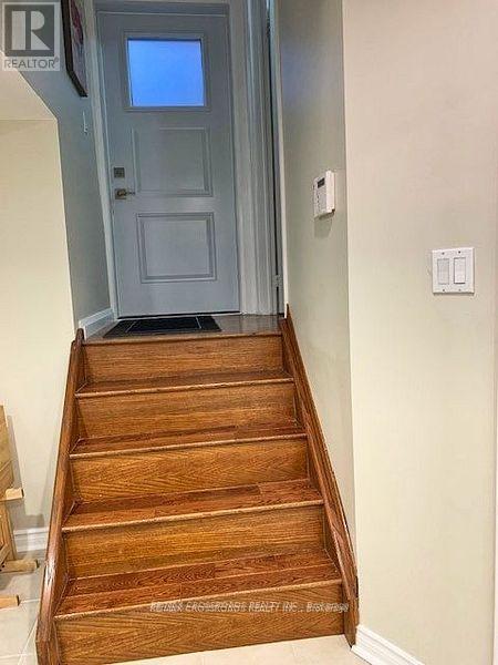 A set of wooden stairs leading to a grey door.