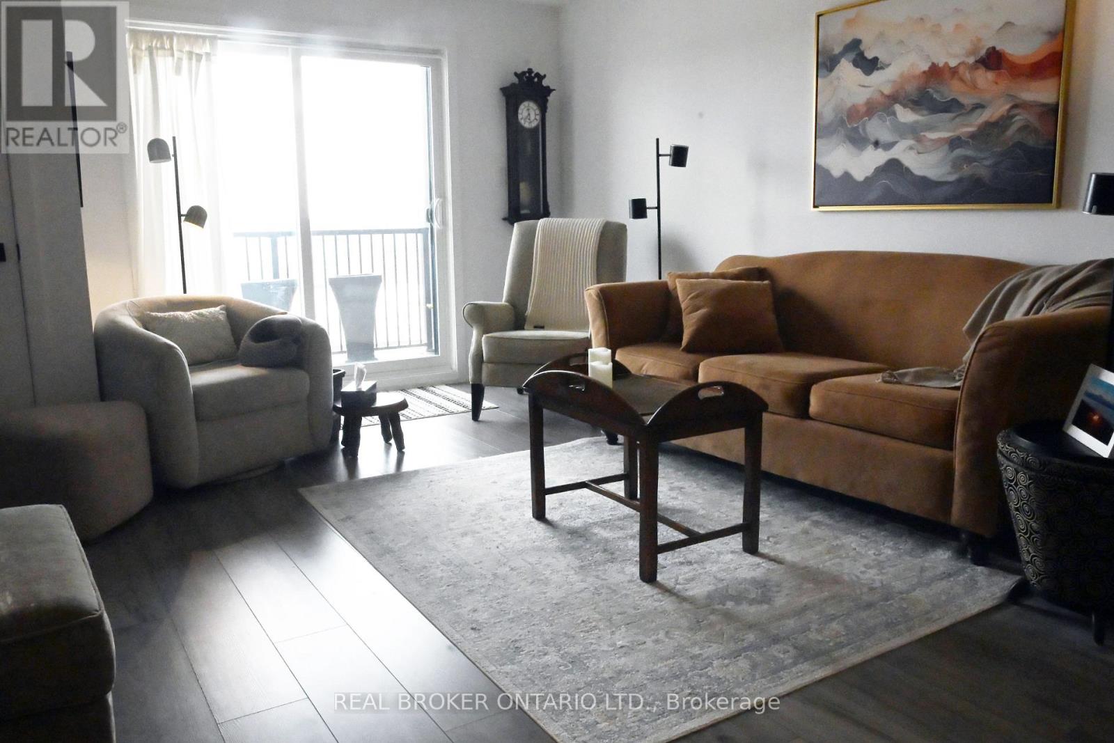 A living room with a large painting on the wall and a couch with a brown throw pillow.