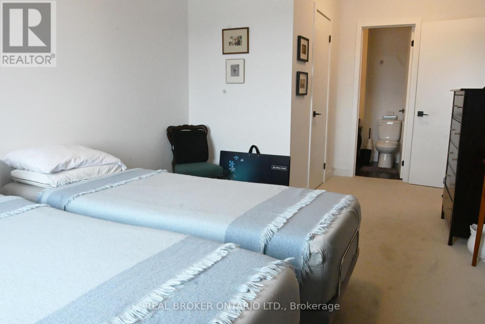 A bedroom with two beds and a black chair.