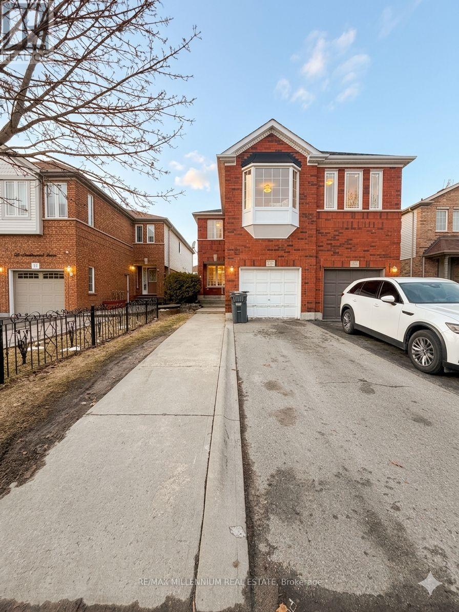 A white car is parked in front of a brick house.