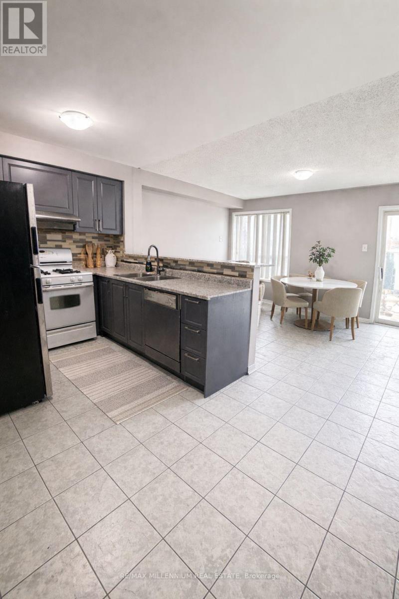 A kitchen with a black refrigerator, a black island, and a white dining table.