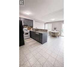 A kitchen with a black refrigerator, a black island, and a white dining table.