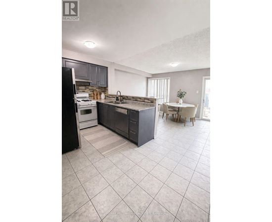 A kitchen with a black refrigerator, a black island, and a white dining table.