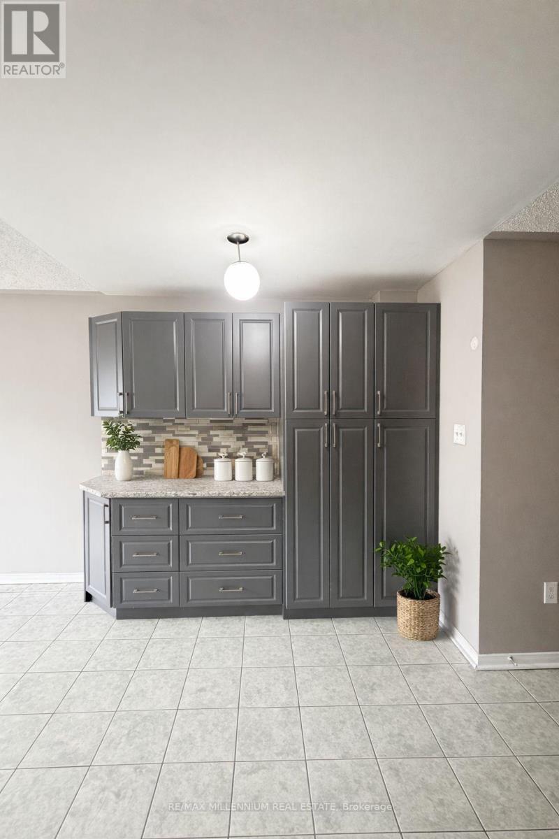 A kitchen with grey cabinets and a countertop with a plant on it.