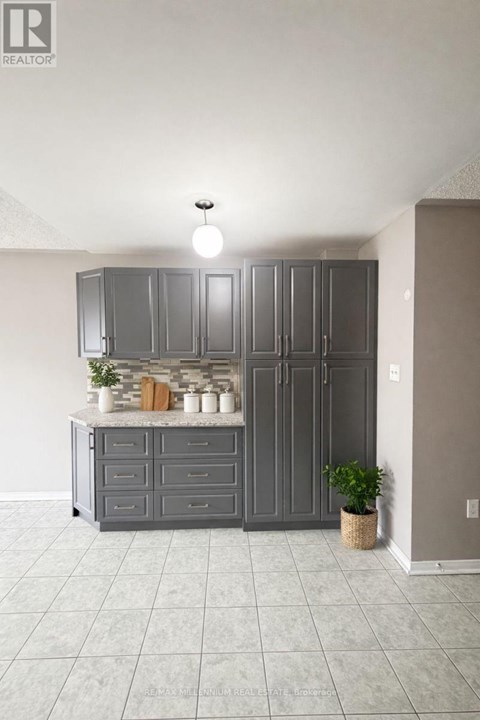 A kitchen with grey cabinets and a countertop with a plant on it.