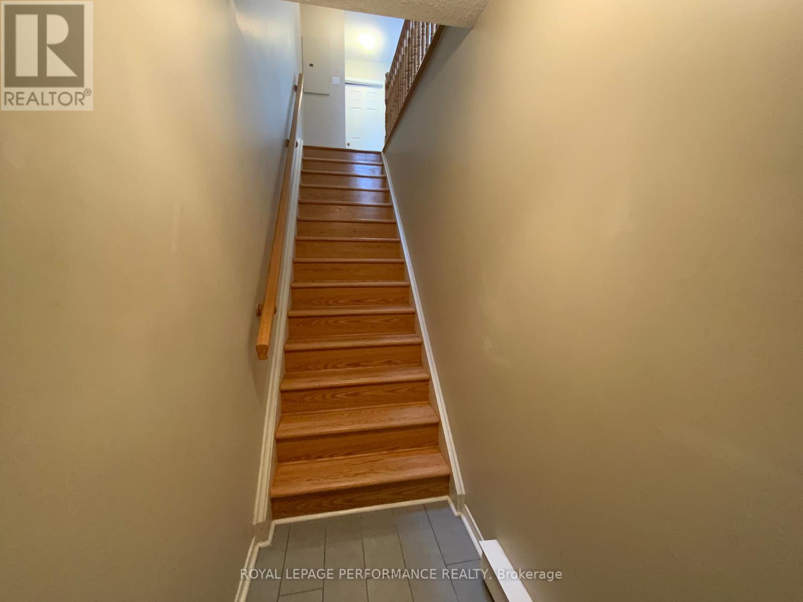 A staircase with wooden steps and a white wall on the side.