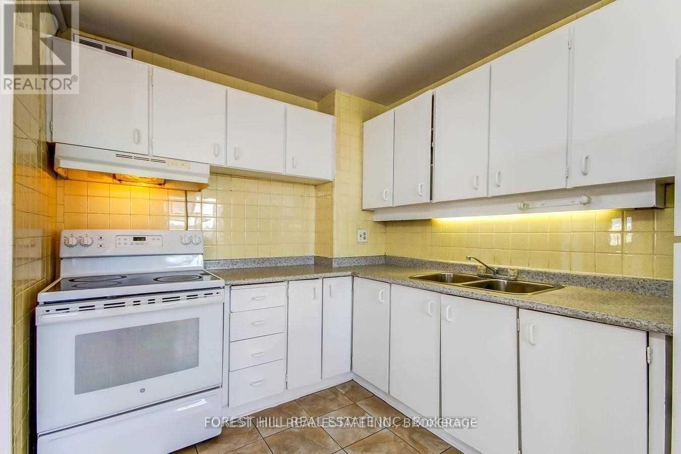 A kitchen with white cabinets and a stove top oven.