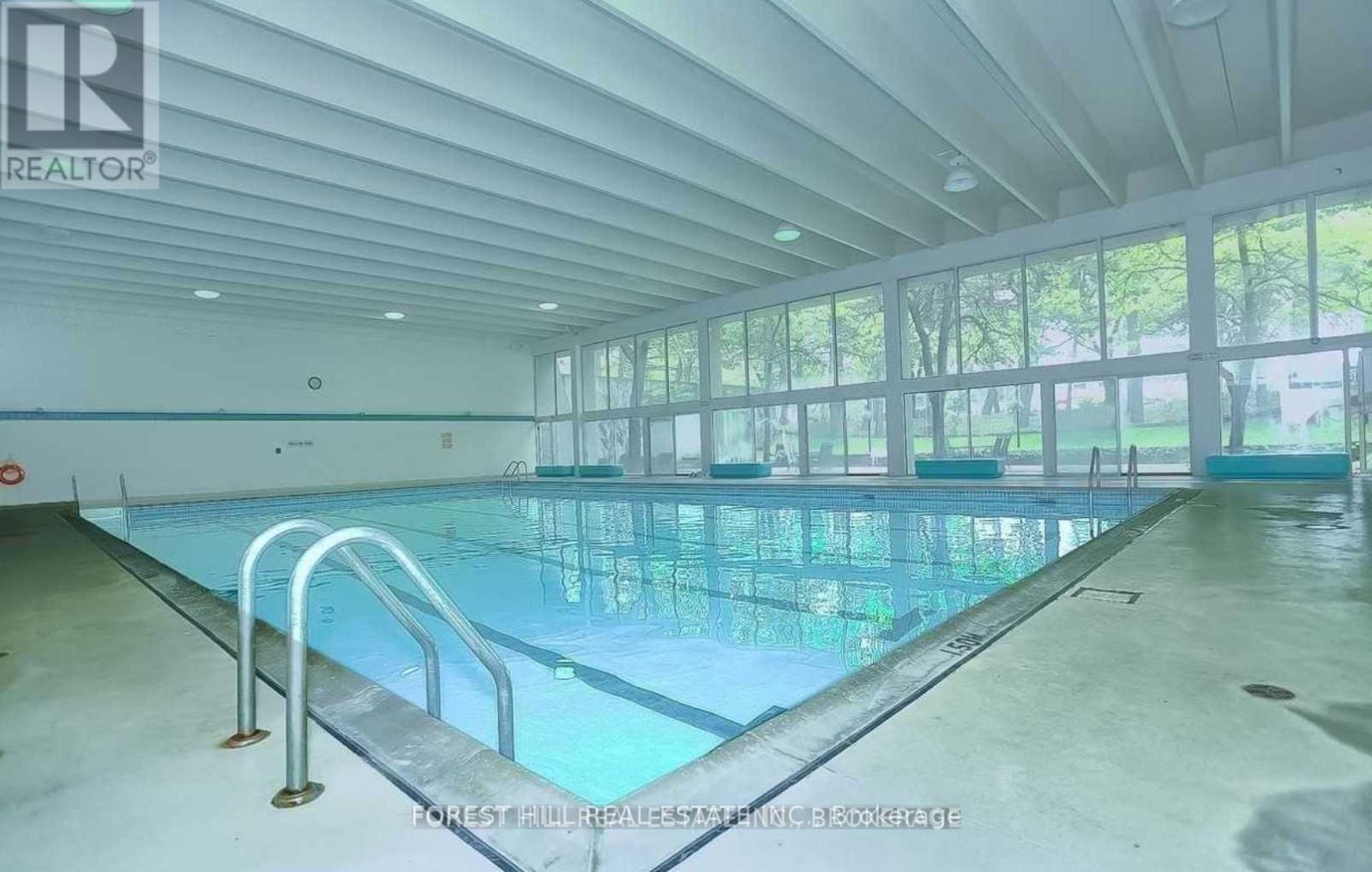 A large indoor swimming pool with a glass bottom and metal railings.