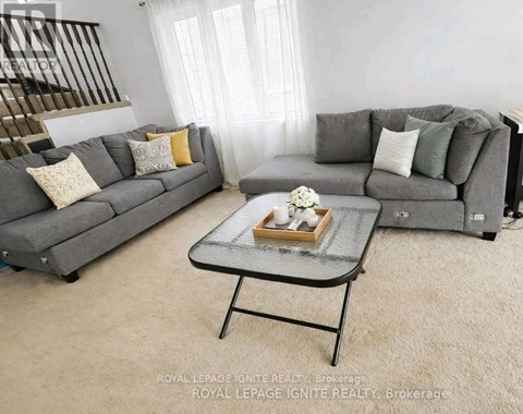 A living room with two grey couches, a glass coffee table, and a small table with a vase of flowers.