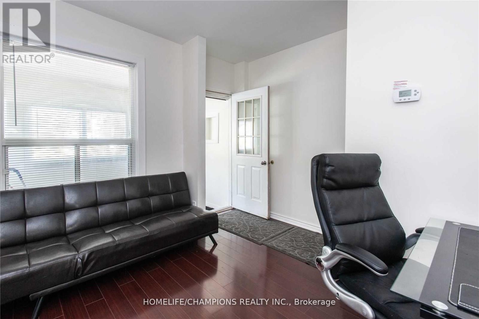 A black leather sofa sits in a bright room with a black chair and a small table.