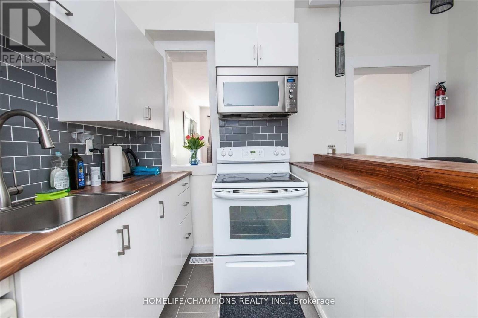 A kitchen with white cabinets and a stove top oven.