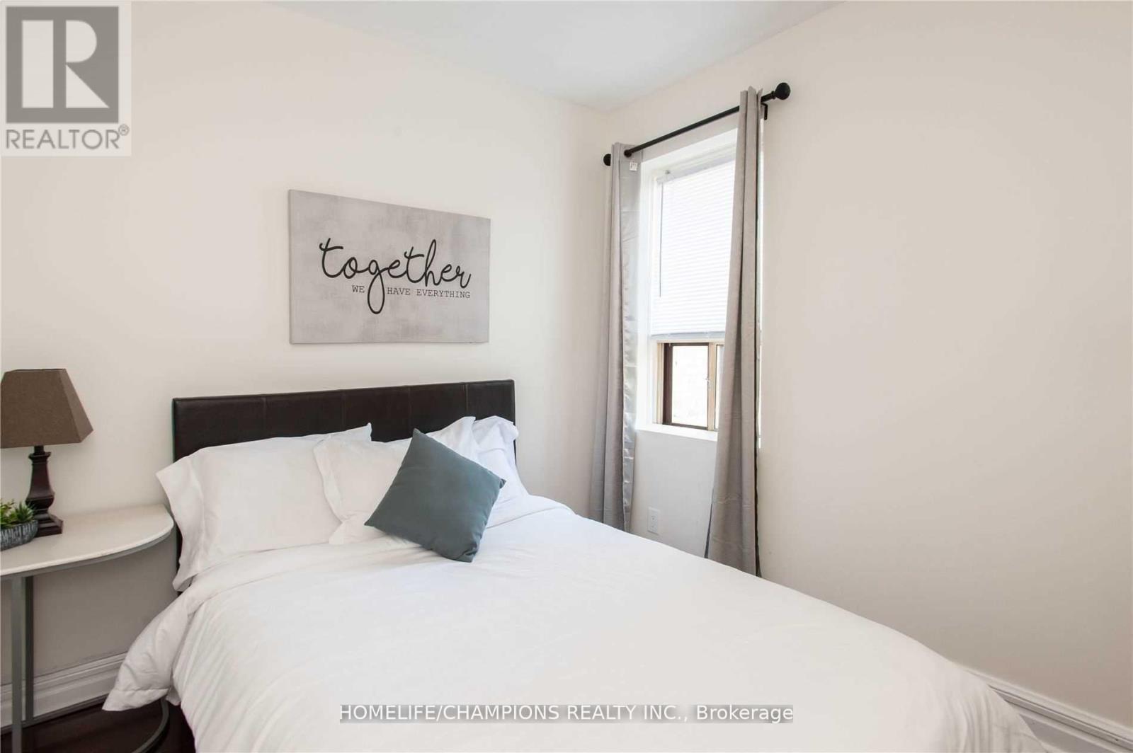 A bedroom with a white bed and a sign that says "together" on the wall.